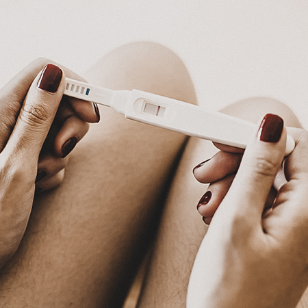 femme tenant un test de grossesse - Maëra Janin vous accompagne dans votre parcours PMA.